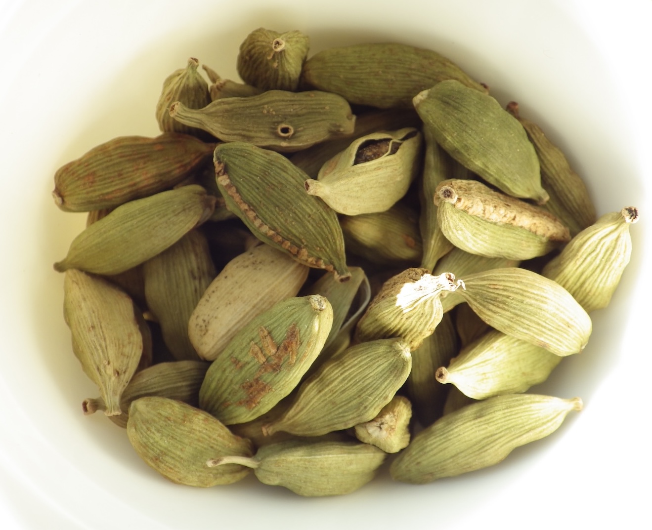 Green cardamom in white bowl