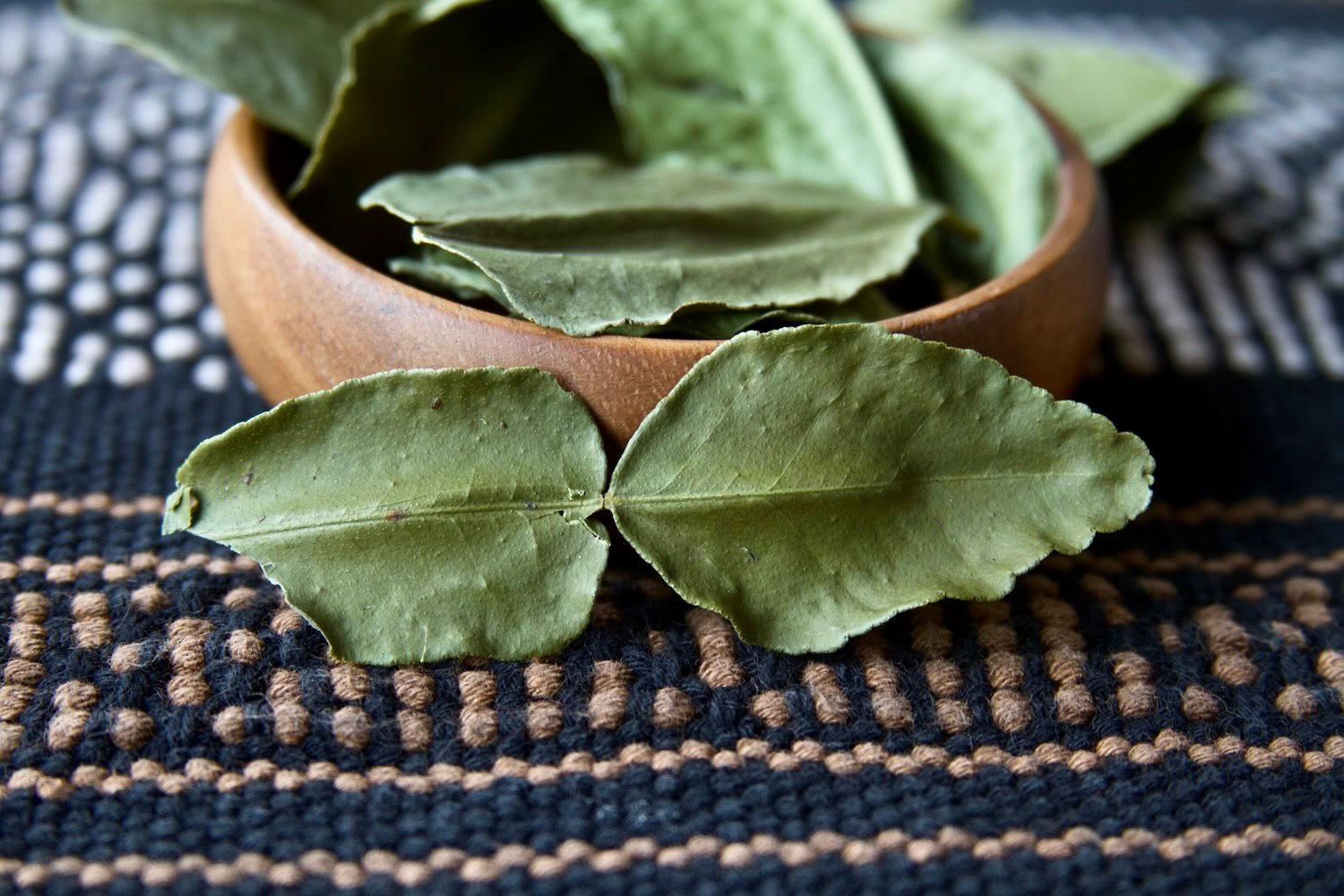 Dried makrut lime leaves on woven fabric