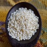 Hulled sesame seeds in black spoon