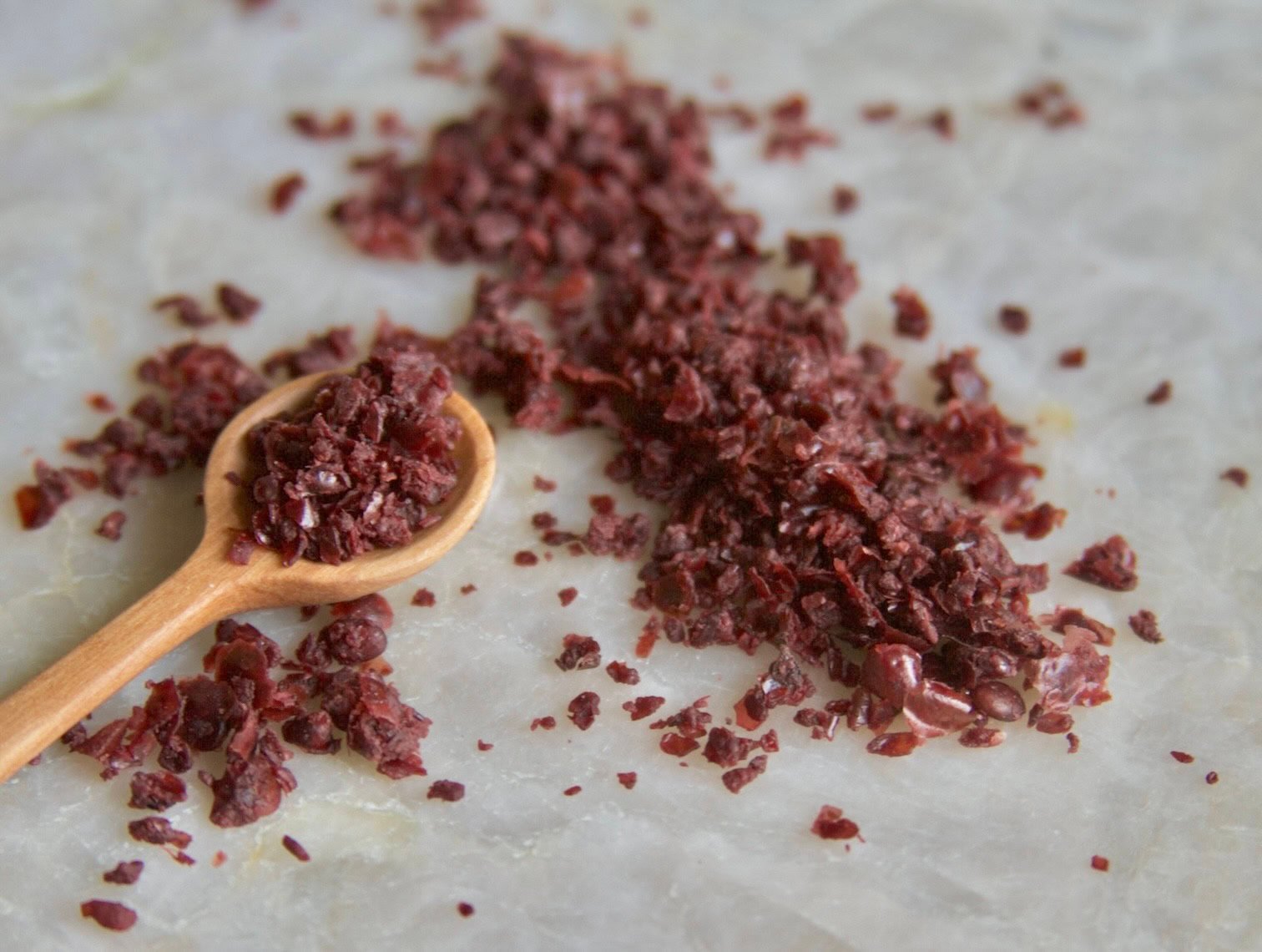Sumac in wooden spoon and on quartz table