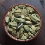 Cardamom pods in ceramic bowl on a wood table