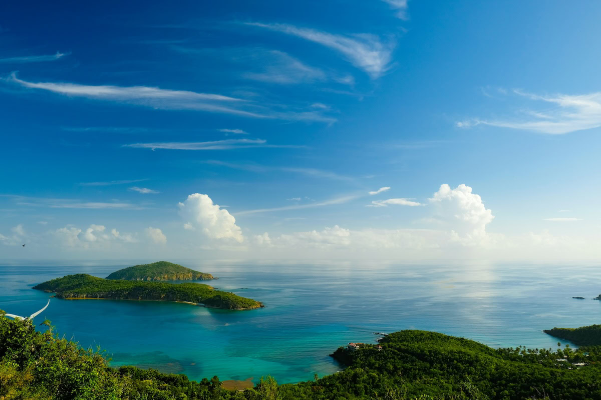 The view from the top of a hill overlooking the ocean with tropical islands and blue sky