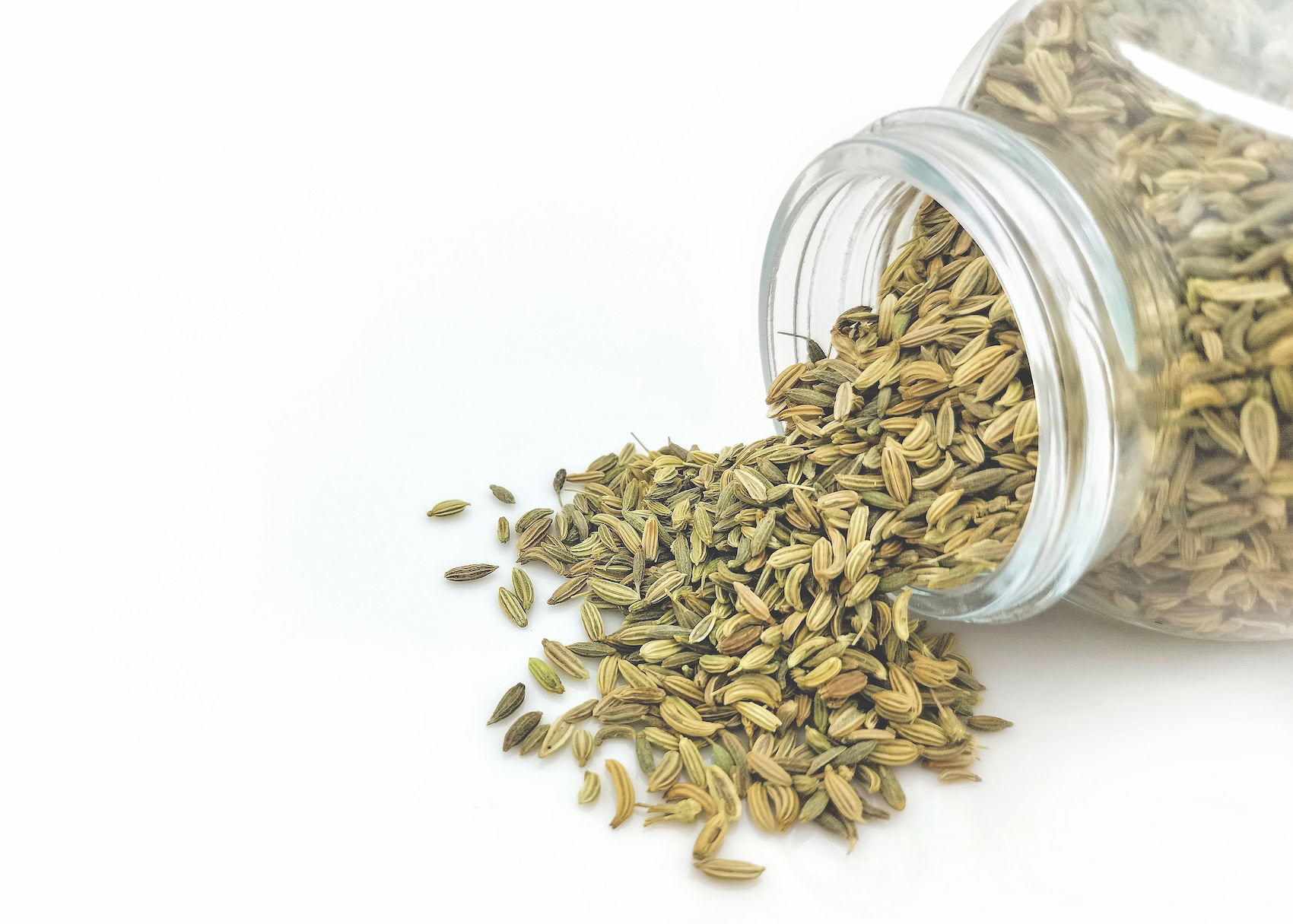 Fennel seed spilling out of a glass jar