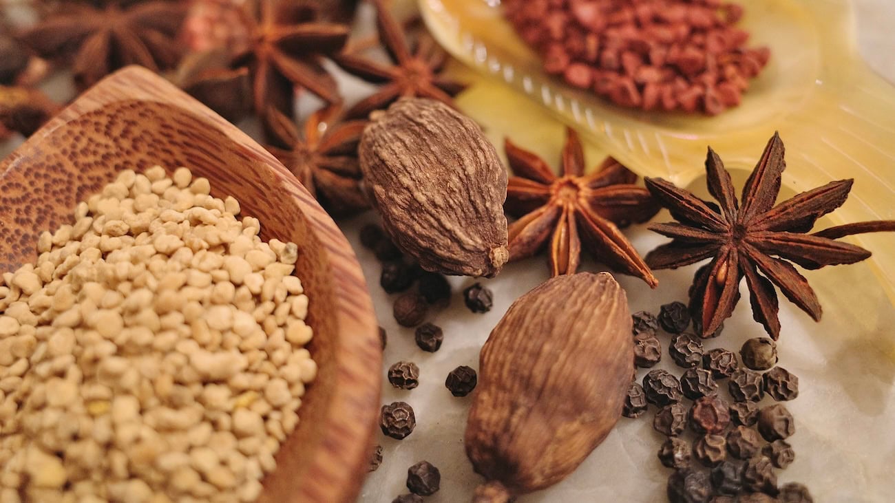 Spice assortment highlighting Chinese cardamom, star anise, and peppercorns