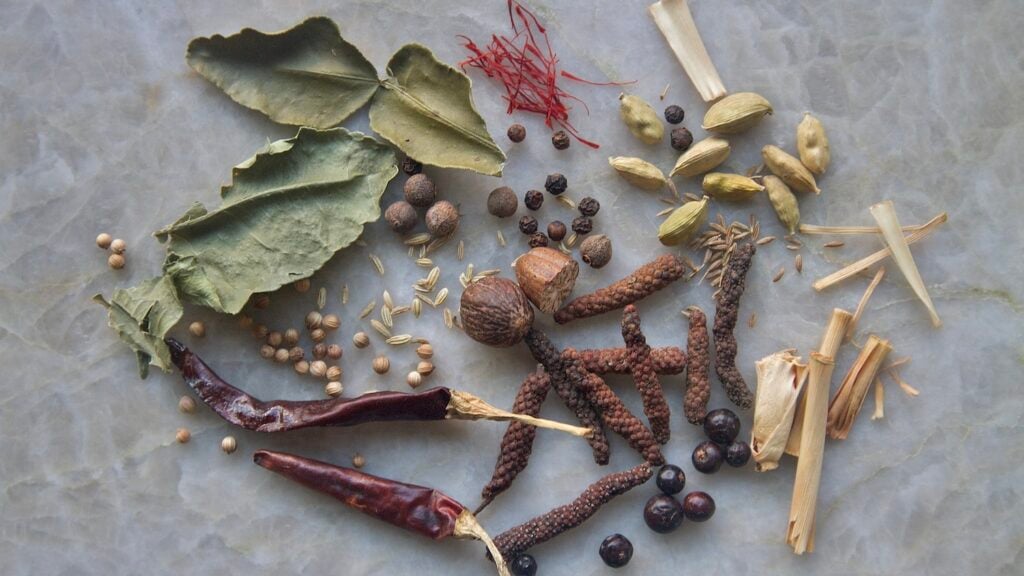 Spice assortment on quartz: chiles, cardamom, fennel seed, corianders, long pepper, juniper berries, peppercorns, saffron
