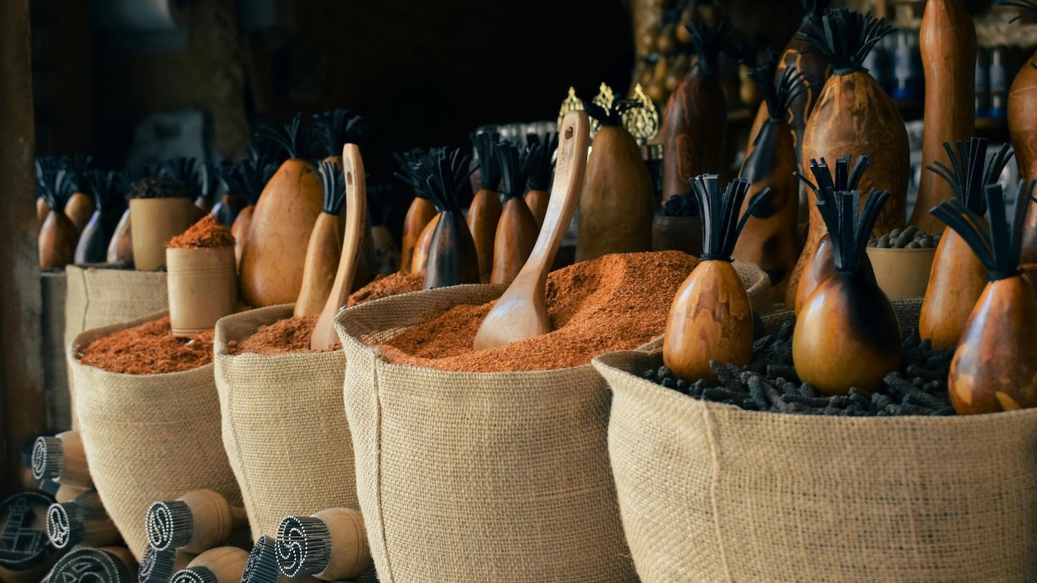 Many different types of spices are in big bags in a spice market.