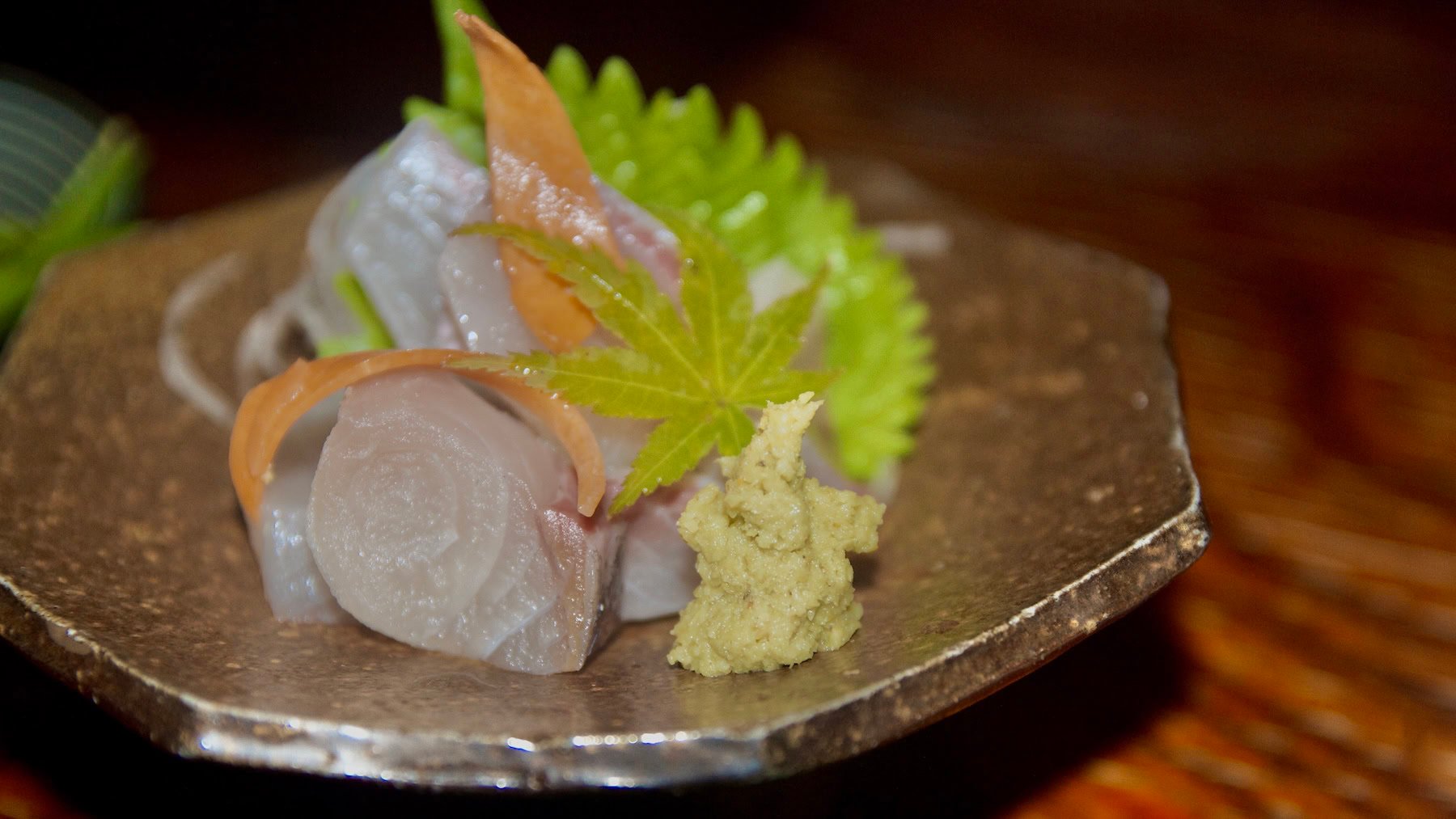 Grated wasabi next to sashimi on an octagonal plate.