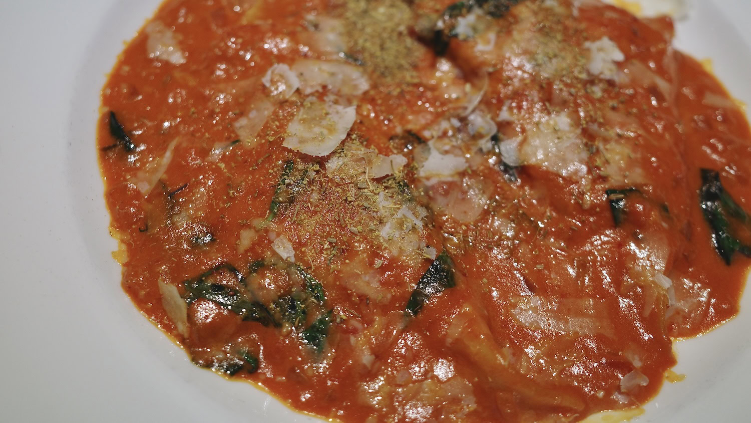 Fennel pollen topping Italian sausage ravioli in a white bowl
