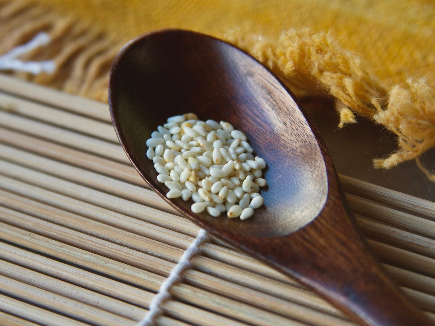 White sesame seed in wooden spoon on bamboo roller