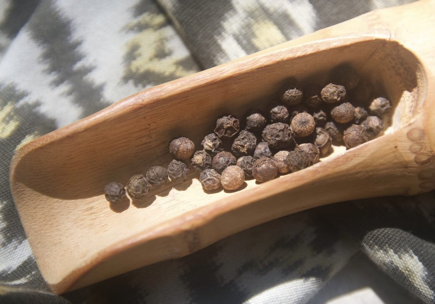 Black peppercorns in a long wooden spoon Black peppercorns in a long wooden spoon