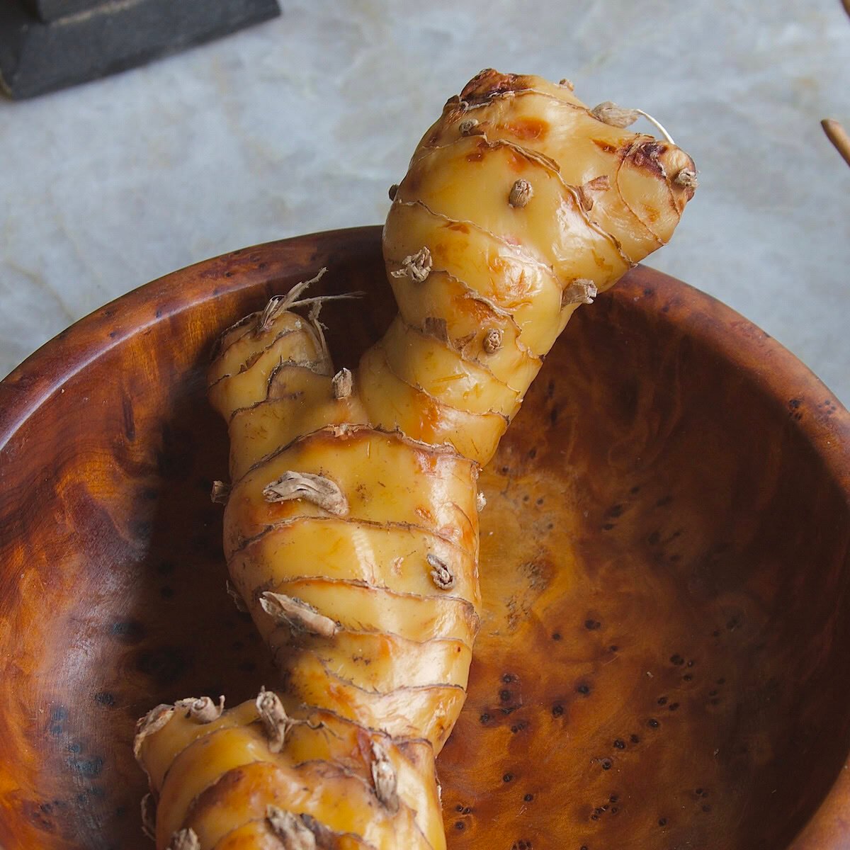 Close-up of galangal rhizome in a wooden bowl