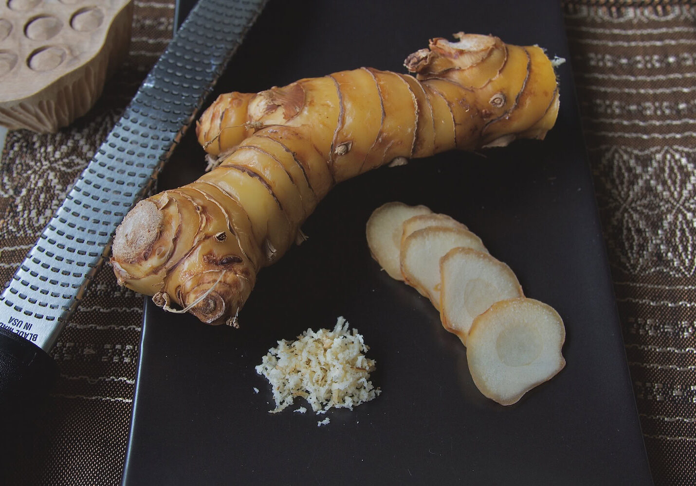 Galangal, sliced and grated, with a microplane next to it