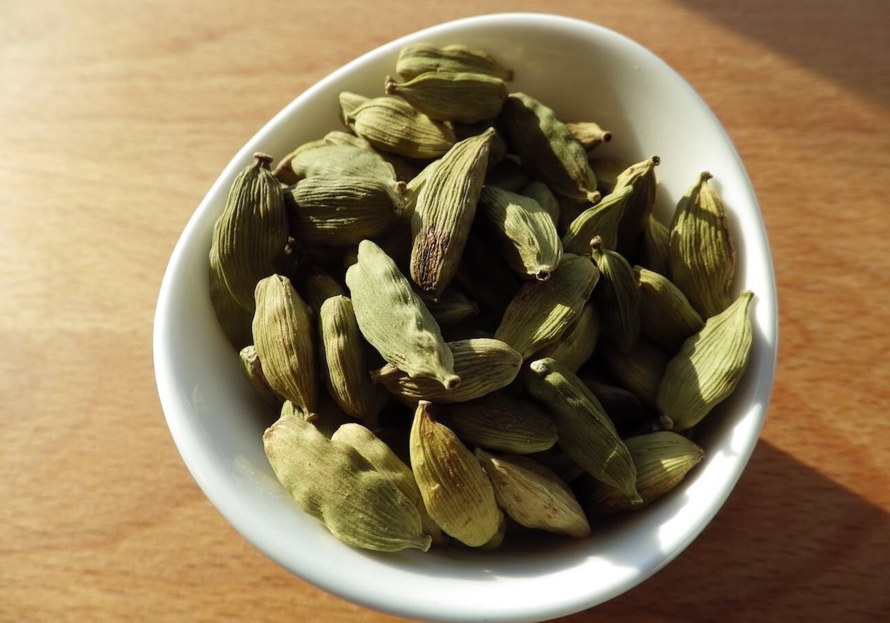 Green cardamom pods in white bowl