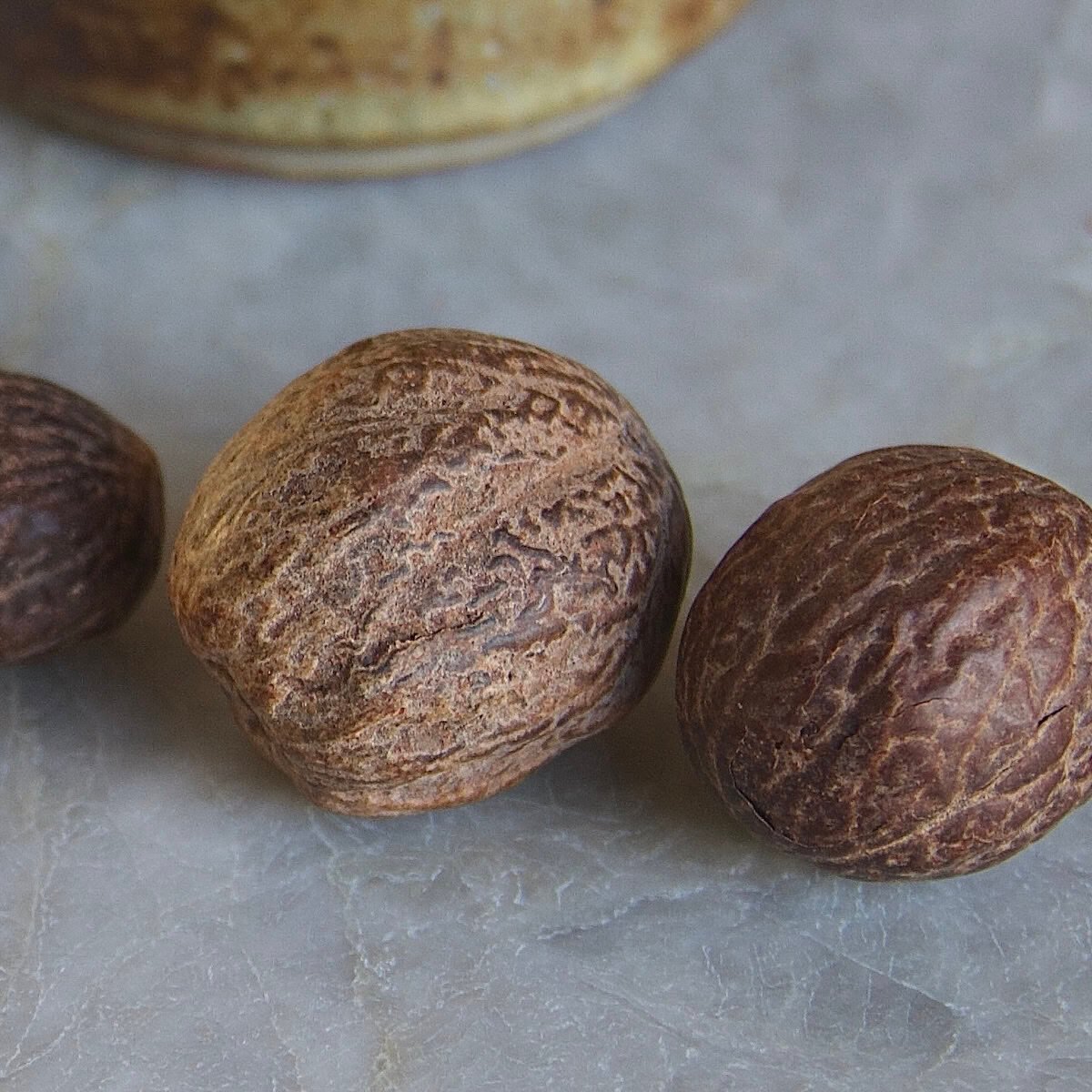 Close-up of whole nutmeg kernels on a quartz countertop
