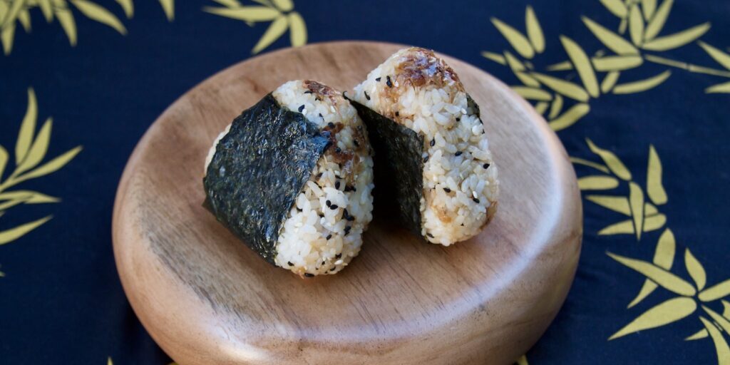 Okaka onigiri on wooden plate against bamboo fabric