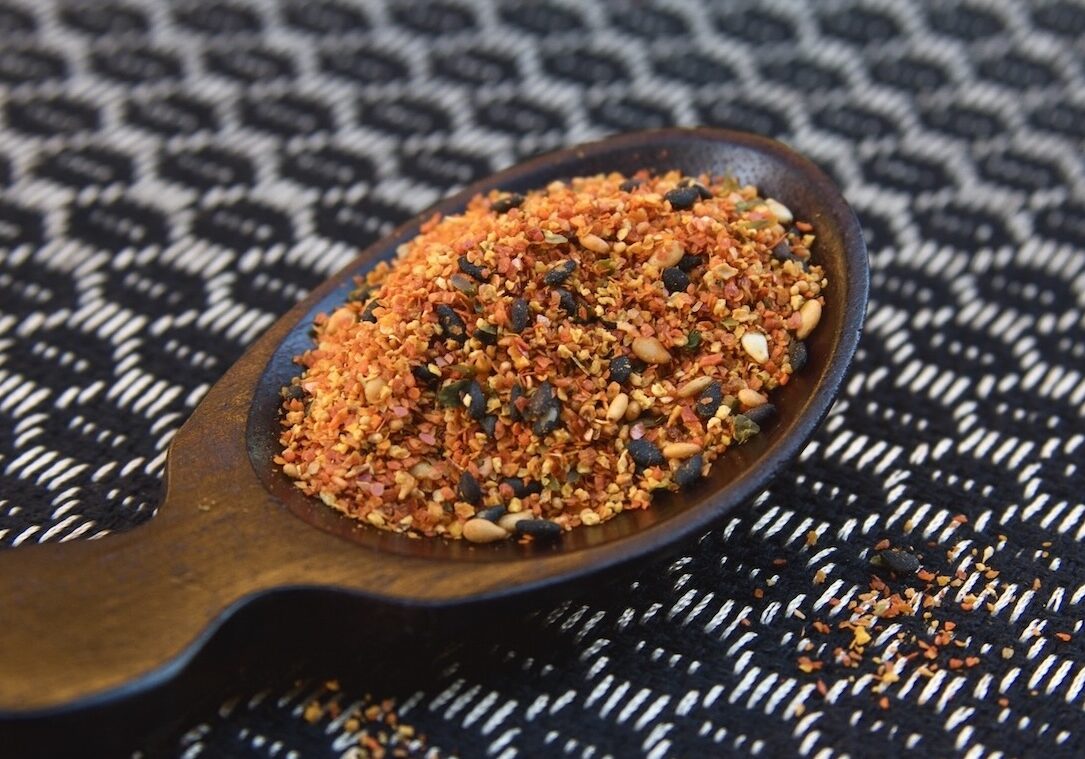 Shichimi togarashi in brown spoon on black and white fabric