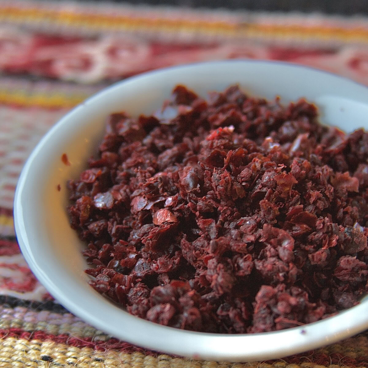 Sumac in a white bowl on woven patterned fabric