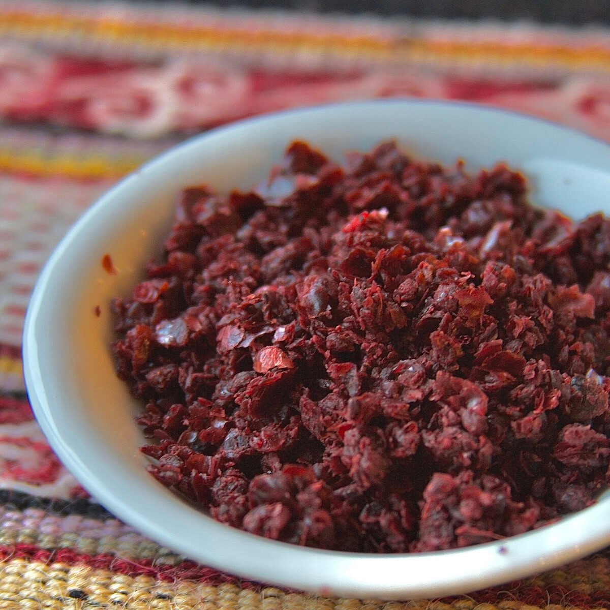 Sumac in a white bowl on woven patterned fabric