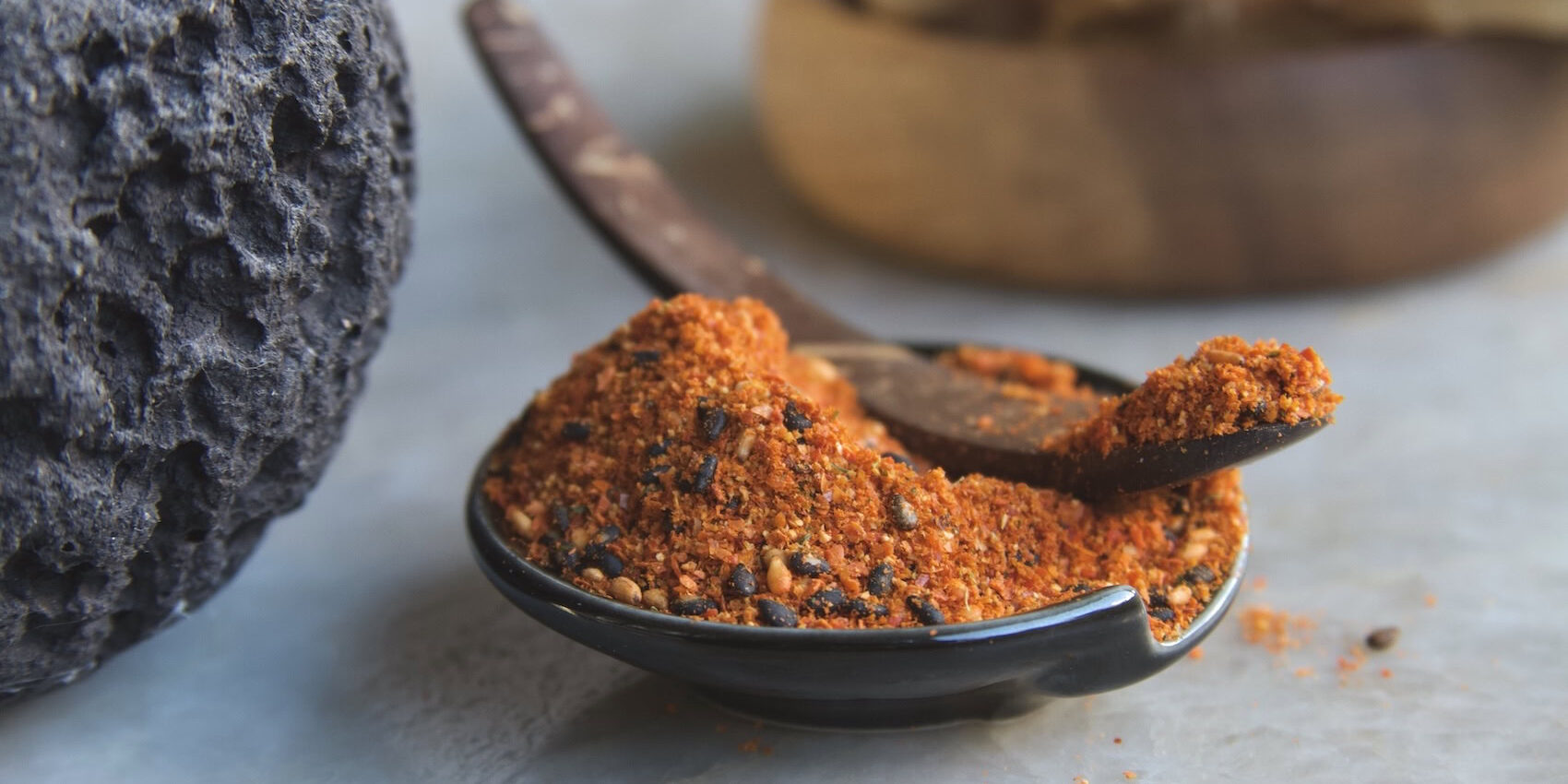 Shichimi togarashi in black dish with curved spoon