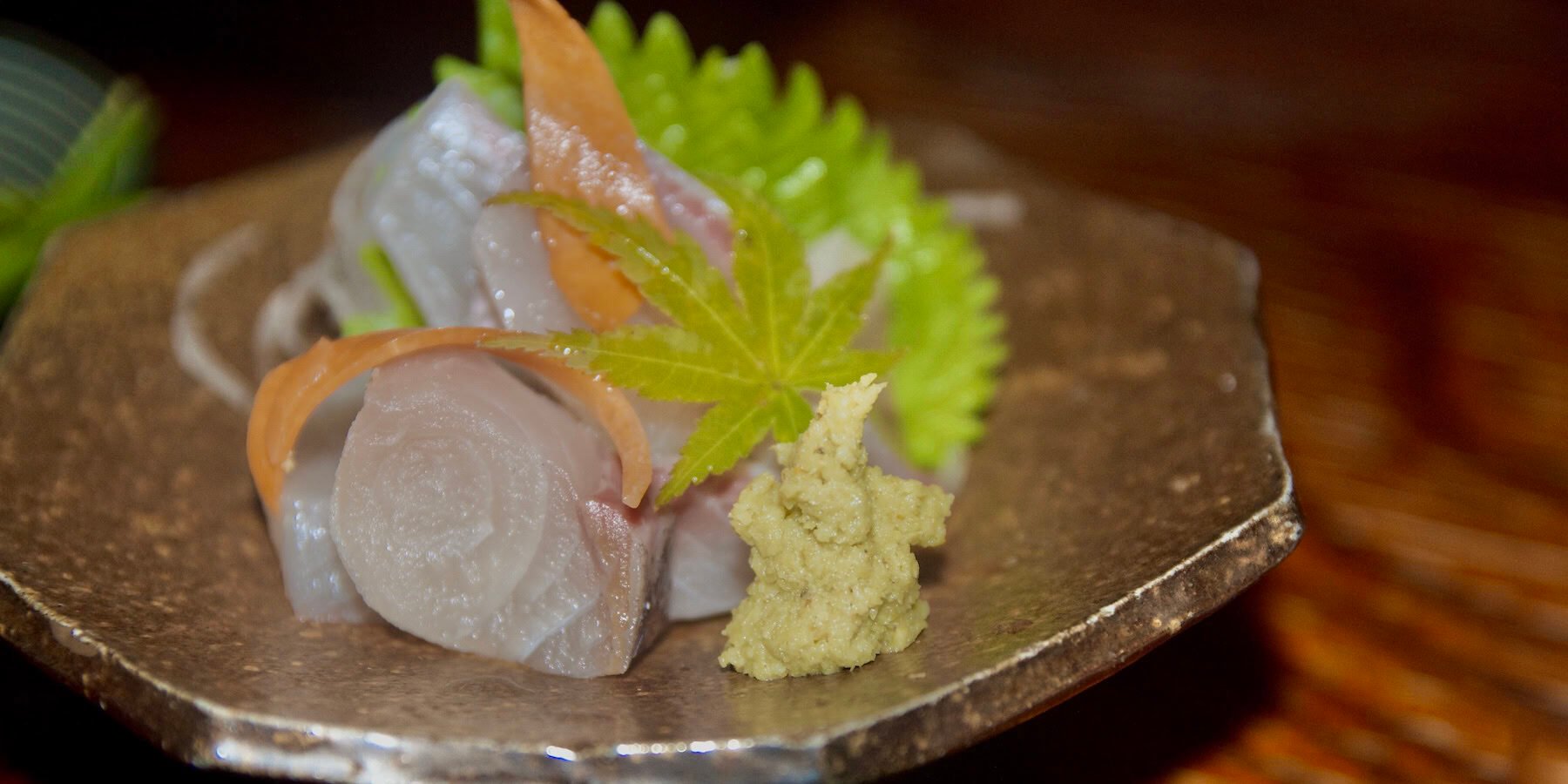 Grated wasabi next to sashimi on an octagonal plate.