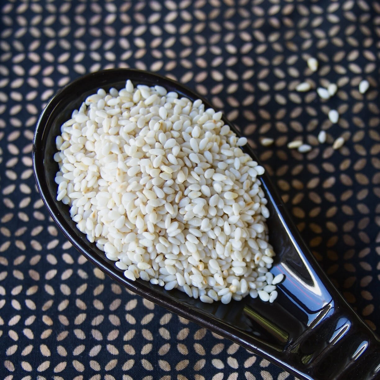 White sesame seed in black spoon White sesame seed in black spoon