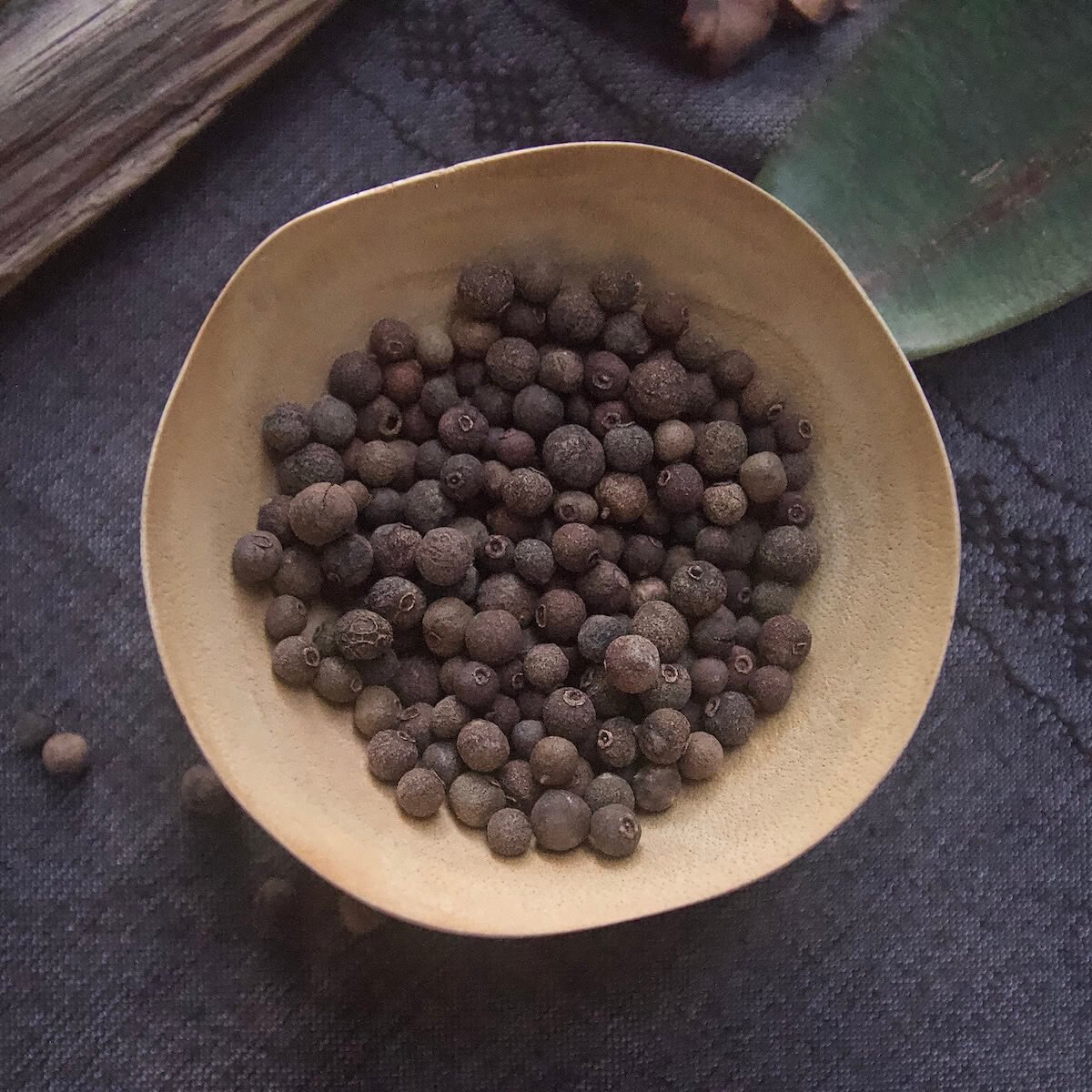 Whole allspice berries in light brown bowl